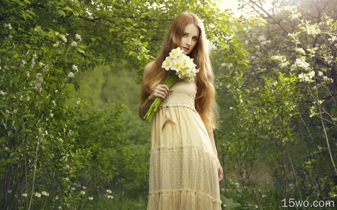 美丽的金发女孩拿着一束鲜花水仙花