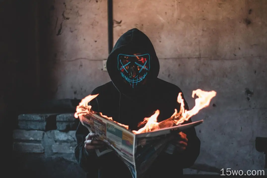 戴面具的家伙在看燃烧的报纸
