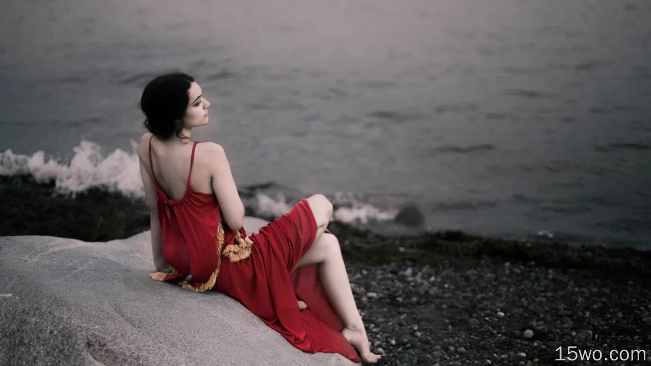 红色礼服的女孩坐岩石海滩8k壁纸